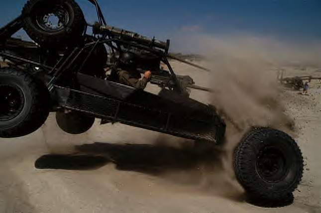 a black off road vehicle with four wheels doing tricks in the desert