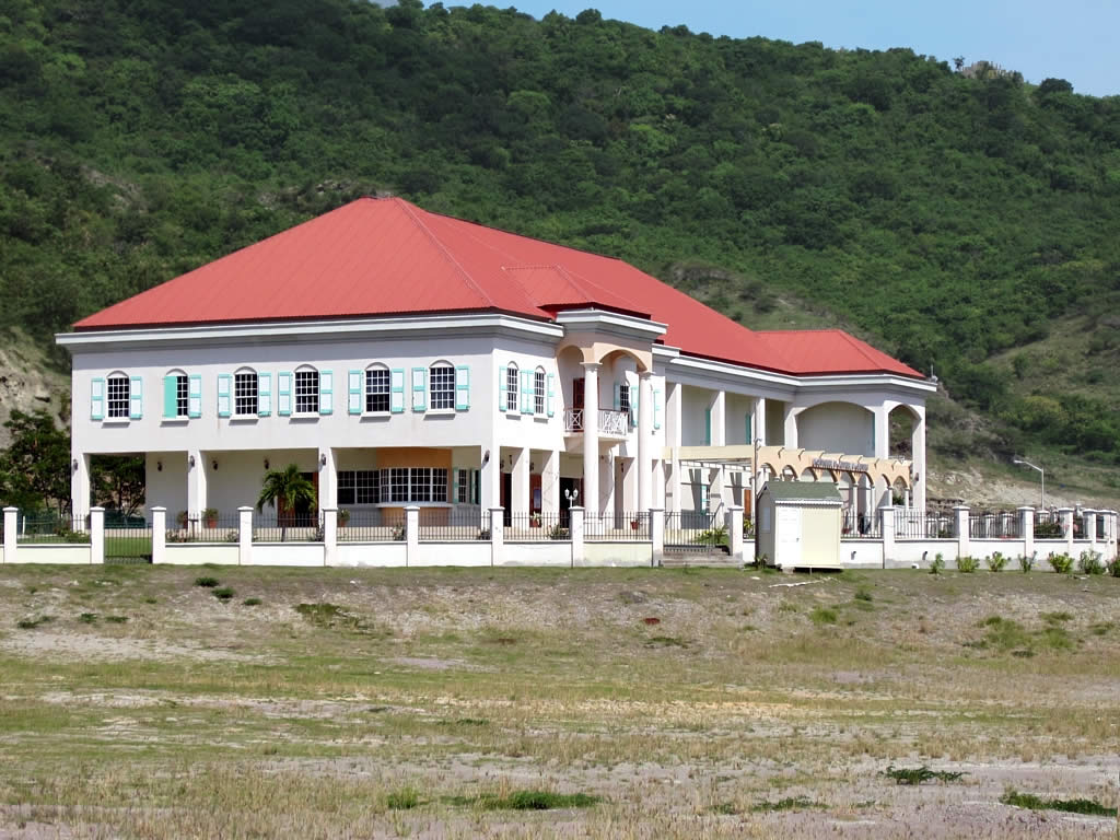 a big white house near the mountains and a field