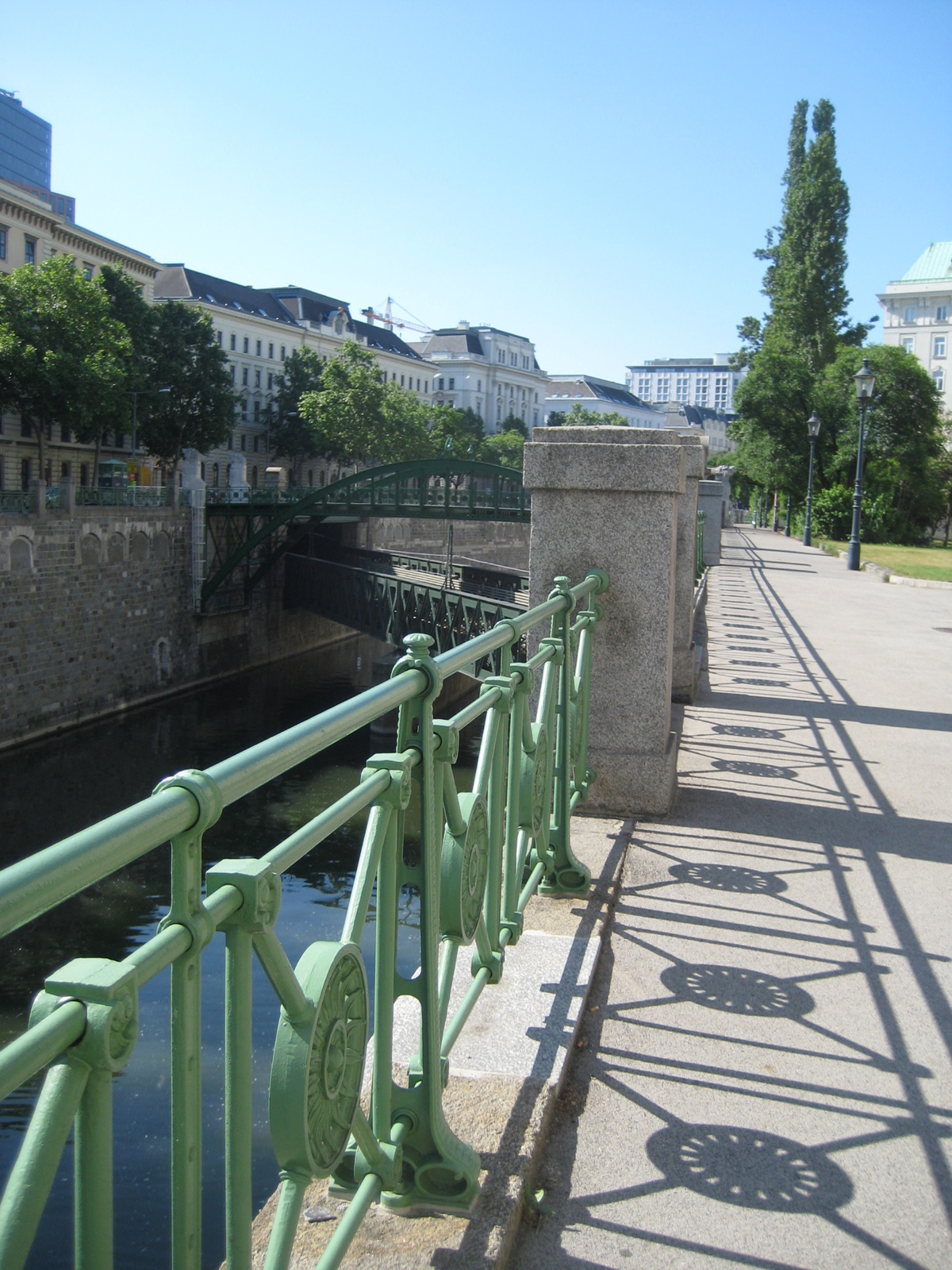 a walkway with green railing next to water