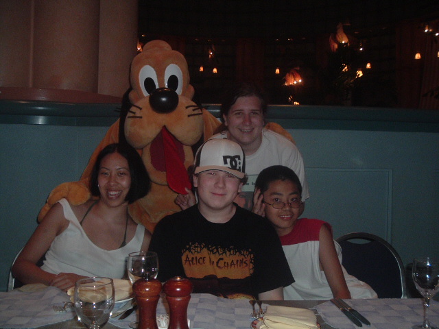a large stuffed animal is posed for a picture at the table with four people