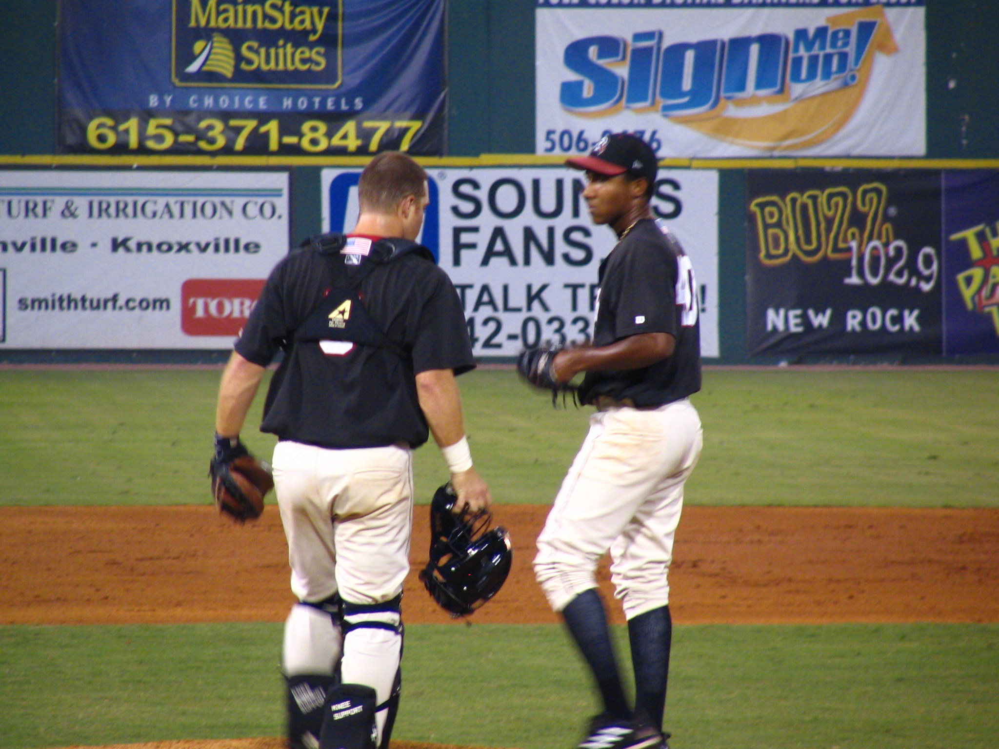 a baseball player standing next to another man on a field