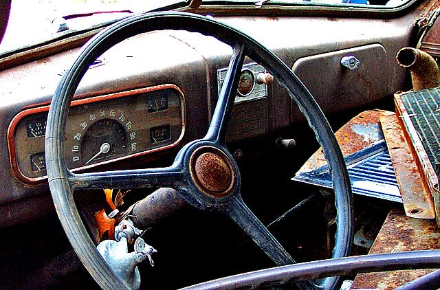 an old vehicle sits in junkyard with rust on it's dashboard