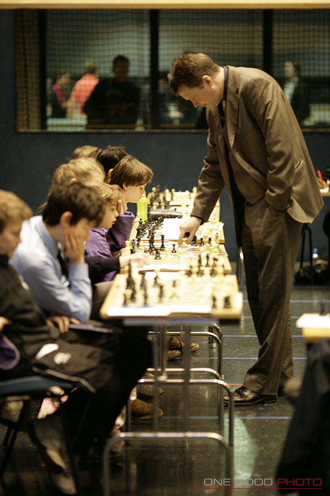 a man is playing chess with some children