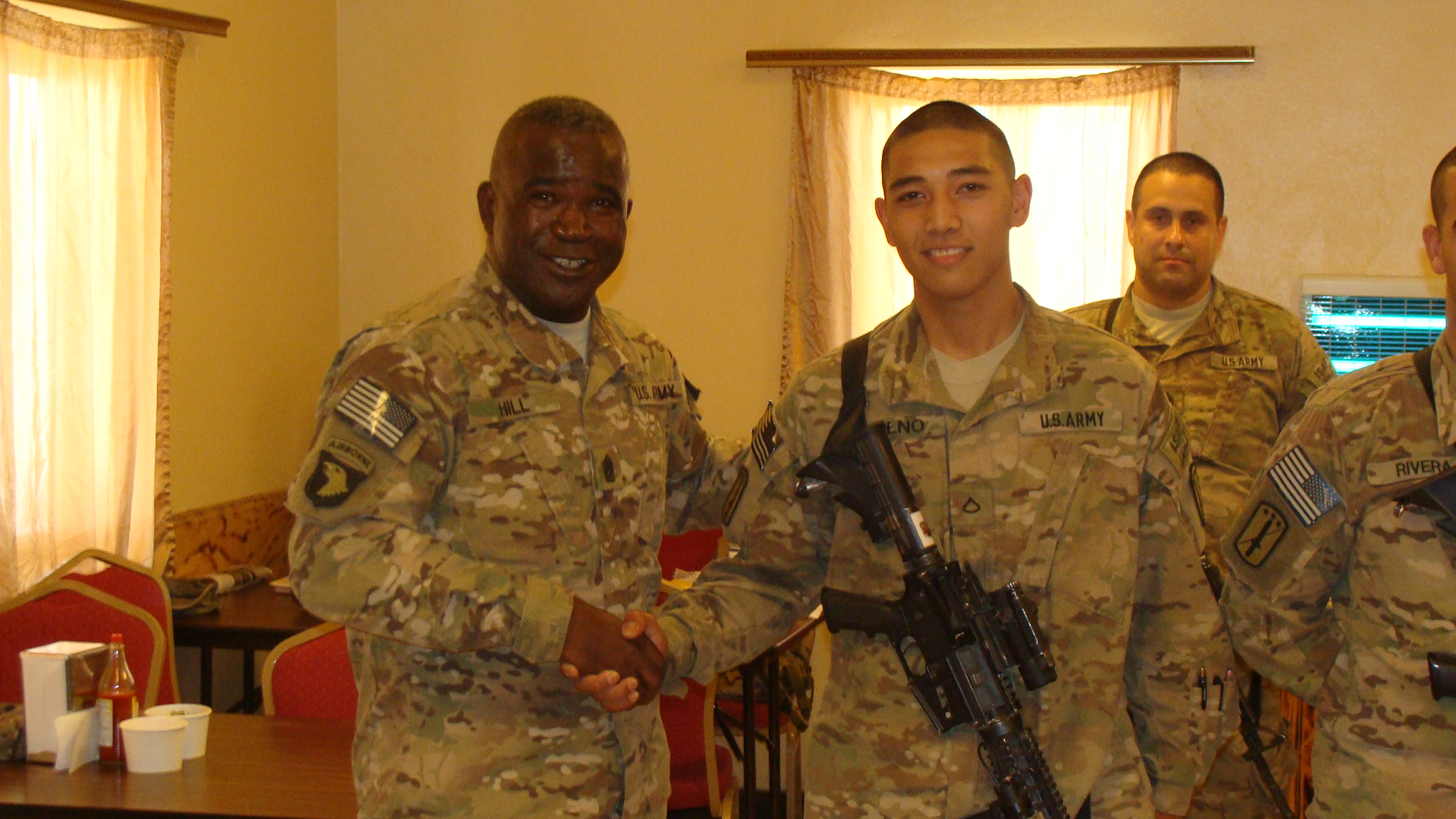 four uniformed men in a room shaking hands