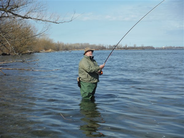 a man stands in the water holding a fishing rod
