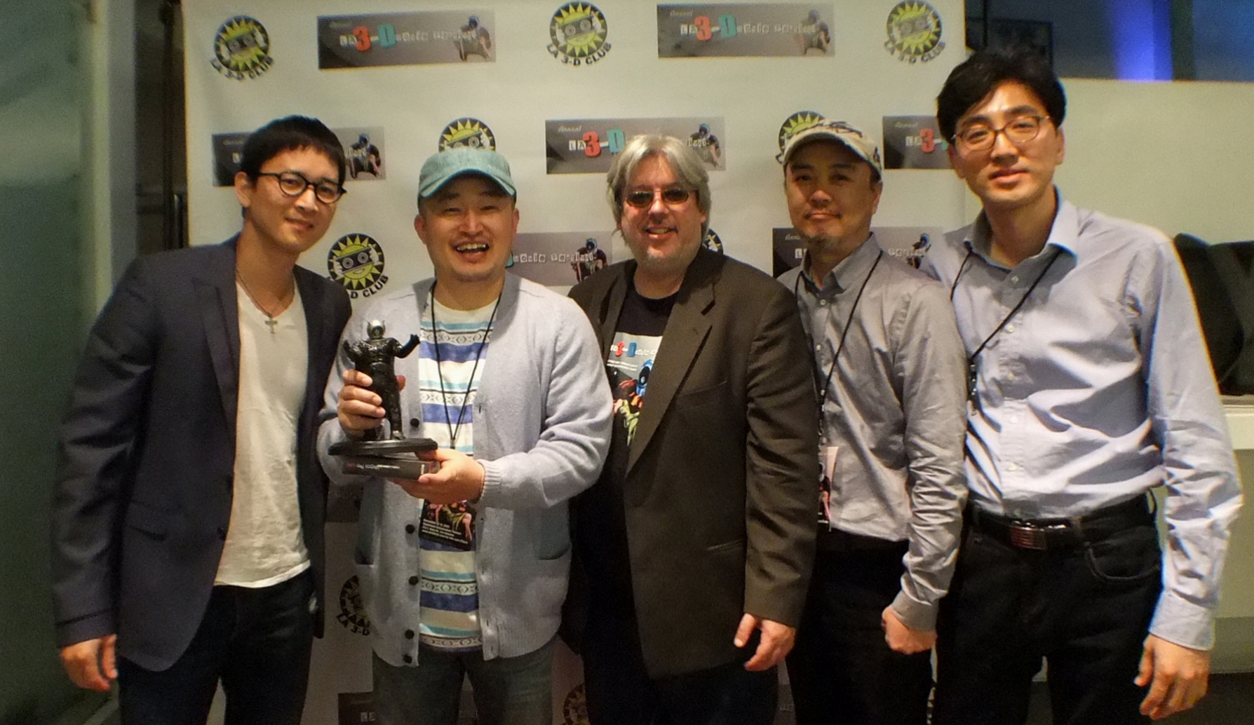 five men posing for the camera with a trophy in his hand