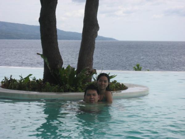 two people sitting in the swimming pool next to the water