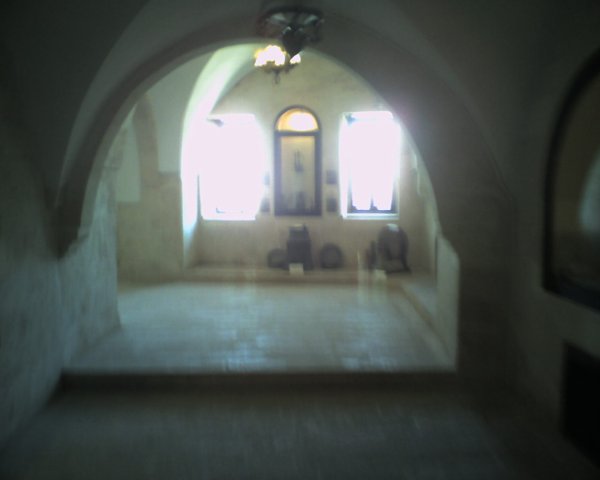 an empty house is seen through a small arched doorway