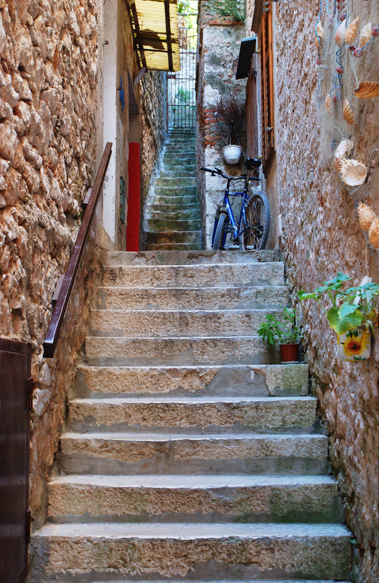 an alley way with some stairs leading to a blue bicycle