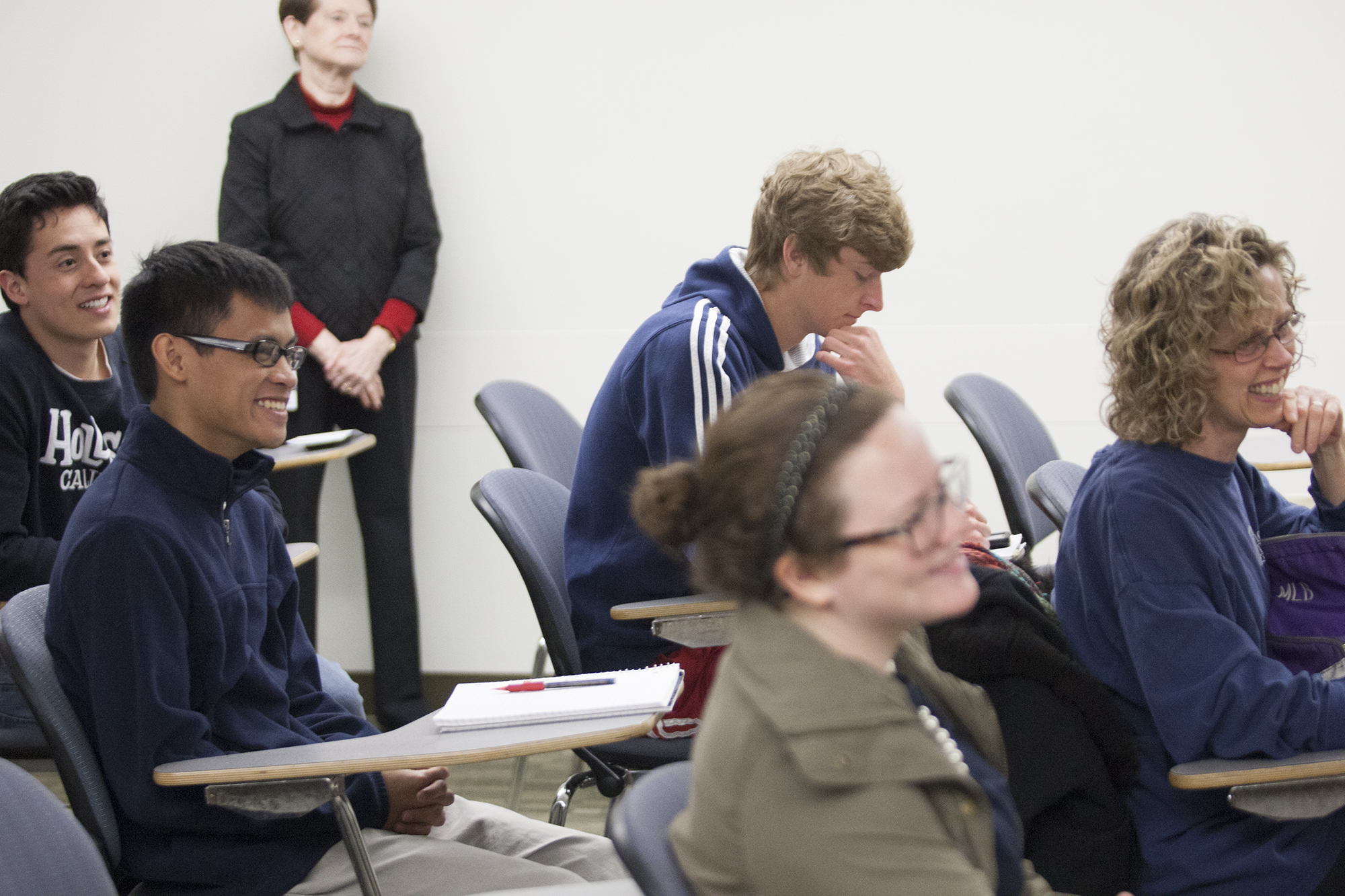 four students sitting in chairs next to each other with papers and pencils