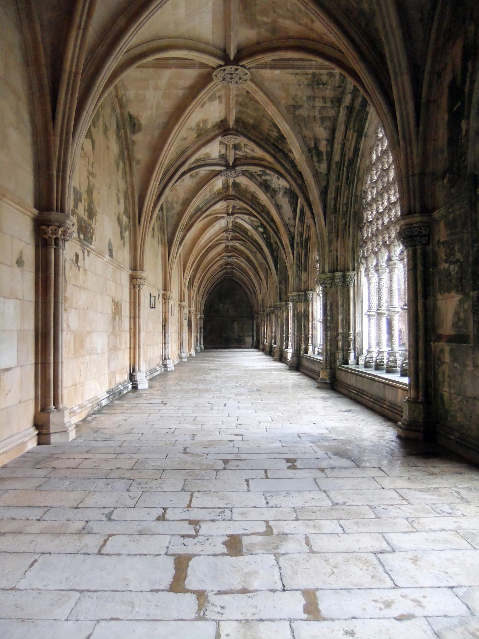 a long hallway lined with stone tiles and arches