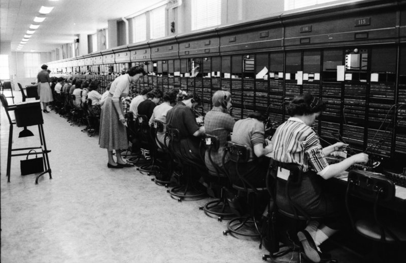 many people are looking at computers in a large room