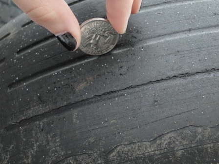 a woman's hand placing a coin into the rim of a tire