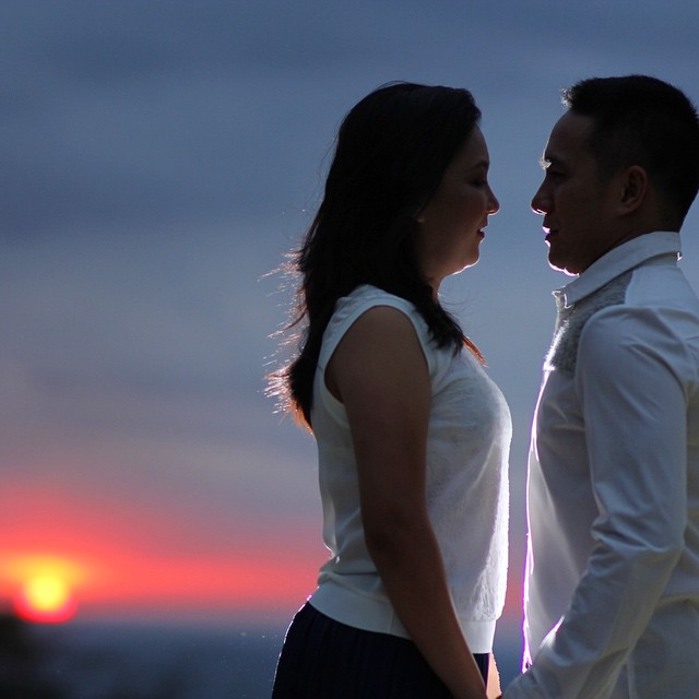 a couple standing together in front of the sun