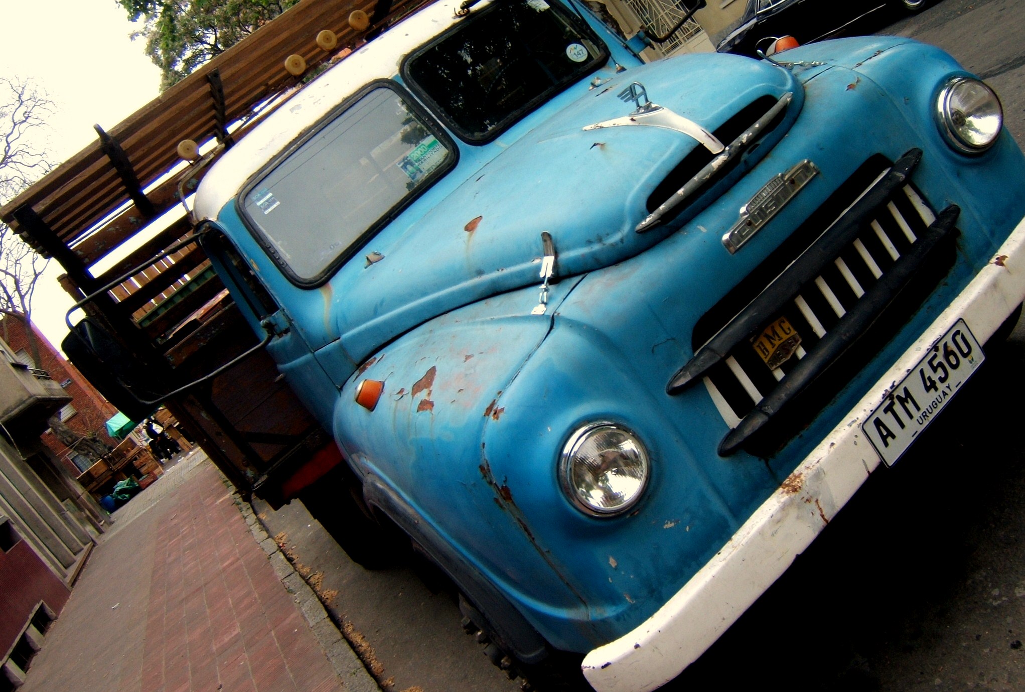 the front of an old blue truck parked on the street