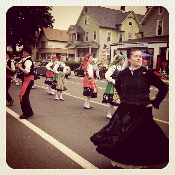 a parade with a woman in a long dress marching through the street