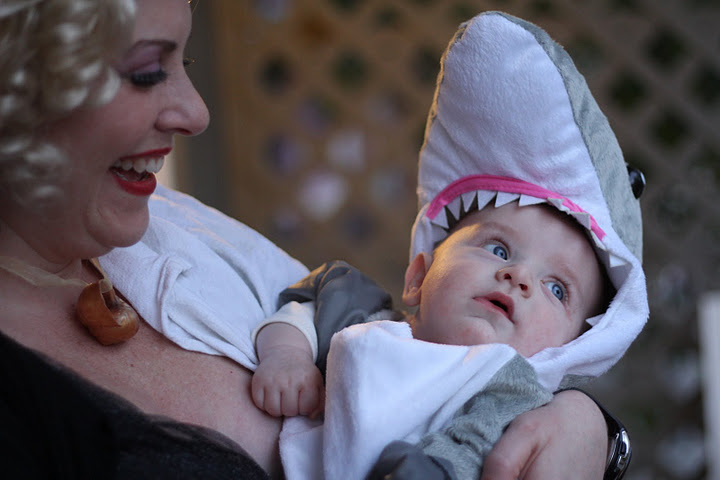 a woman holding a baby wrapped in a shark costume