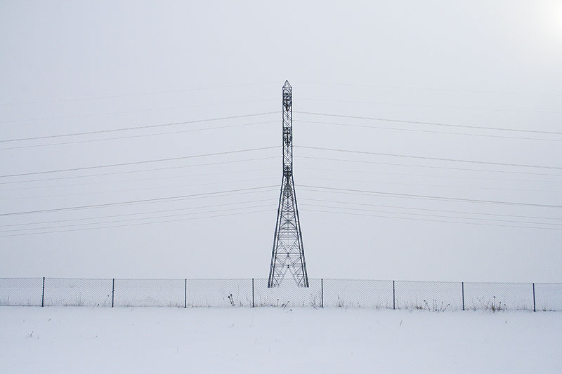 an empty snowy field with a light tower and sky