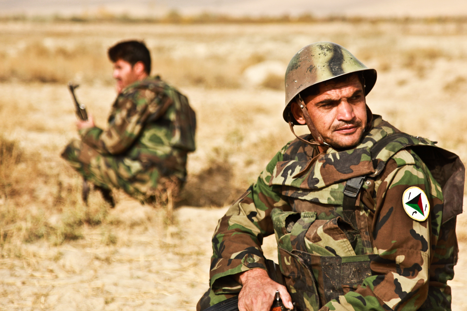 two men in camouflage with rifles on their hands