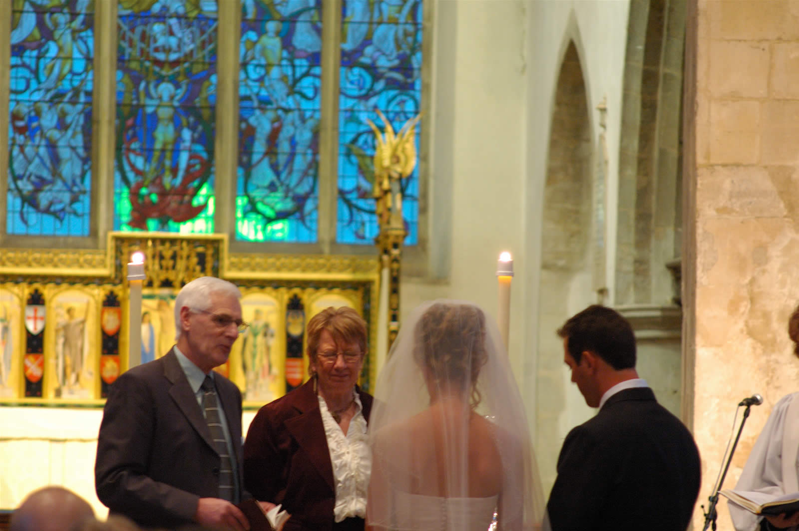 a couple in wedding clothes standing next to each other in front of a priest