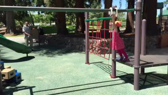 a little girl in pink standing on top of a slide