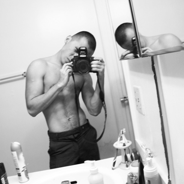shirtless man takes selfie in mirror