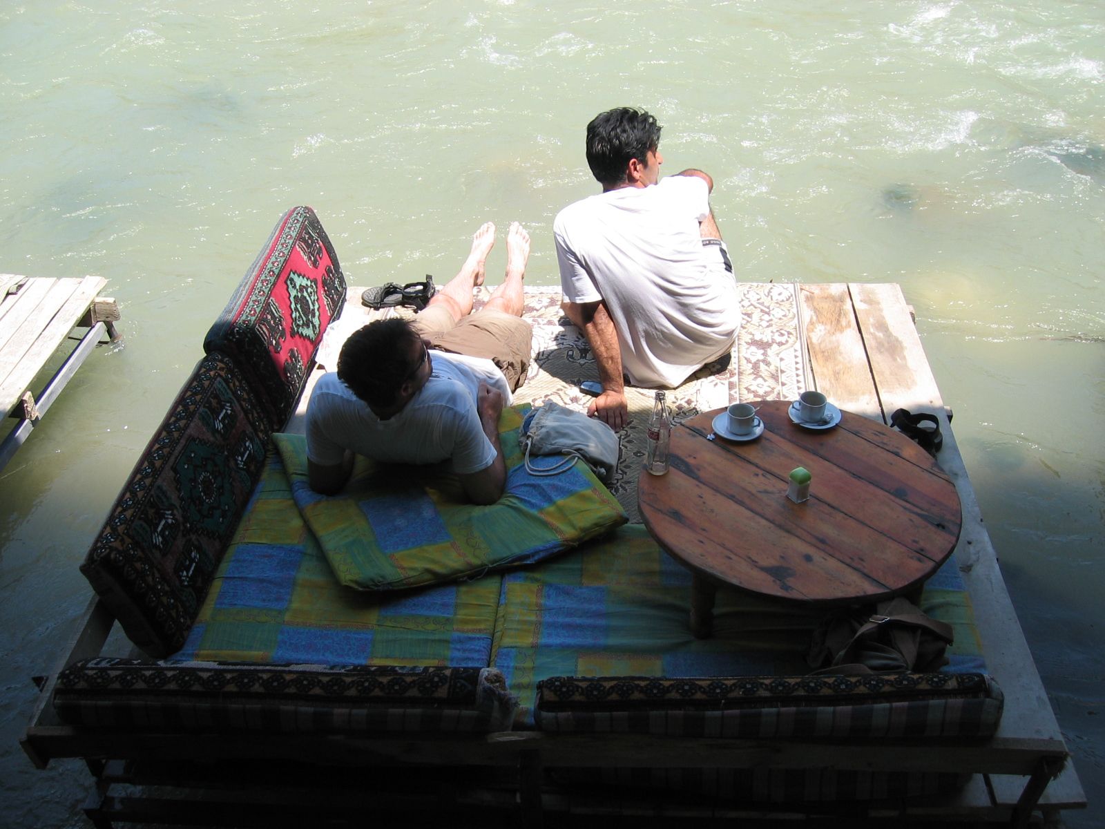 two people are sitting on a pier overlooking the water