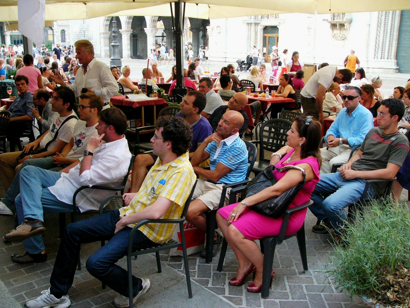 a bunch of people sitting under a large open air umbrella