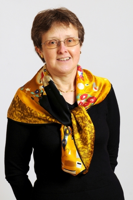 an older woman wearing glasses with a yellow scarf around her neck