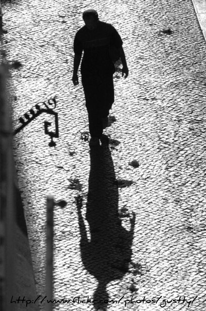 black and white pograph of man walking on the sidewalk