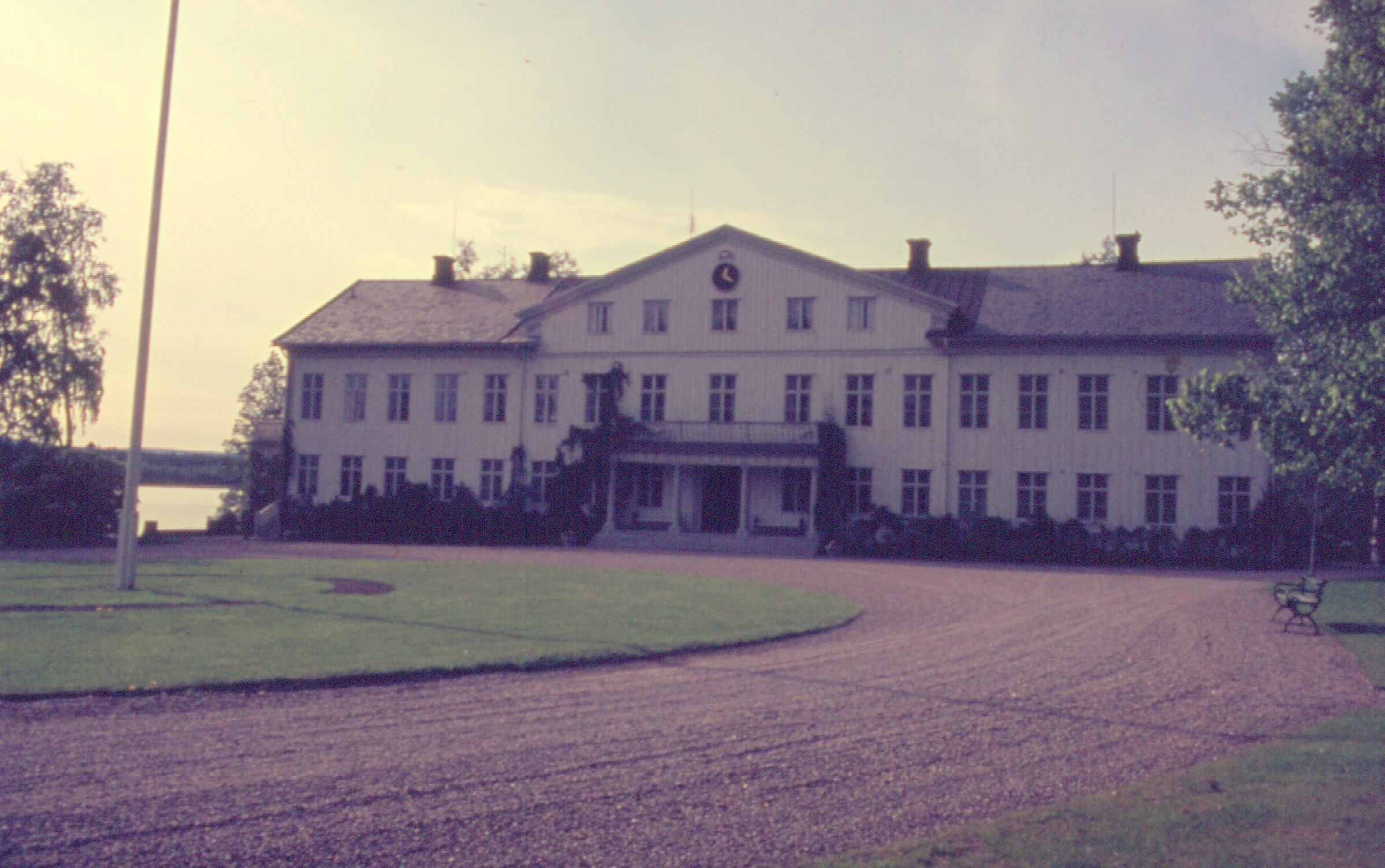 a very tall white house sitting in the middle of a field