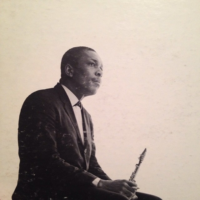 a black and white po of a man in a suit holding a musical instrument
