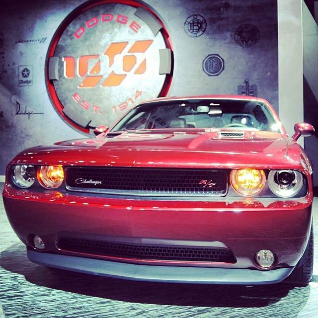 a red car is parked on display at an automobile show