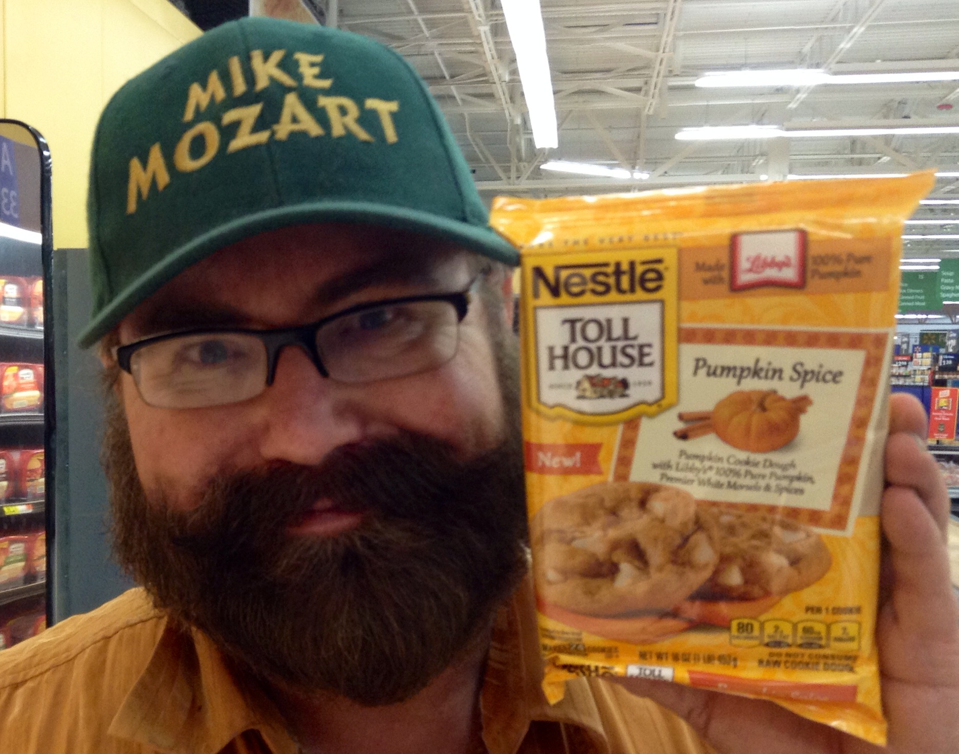 the bearded man with a mustache wearing glasses has a bag of nestle tol house chicken