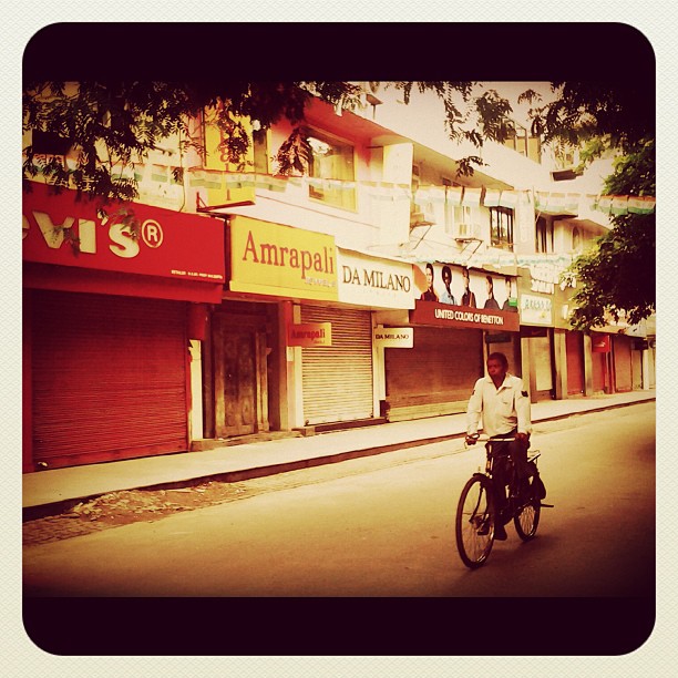 a man on a bicycle drives past businesses