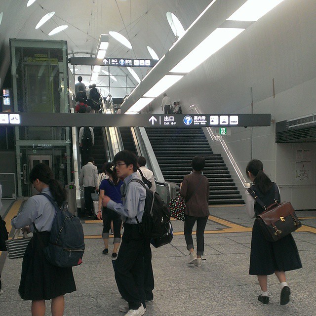 several young women walking down a walkway carrying luggage