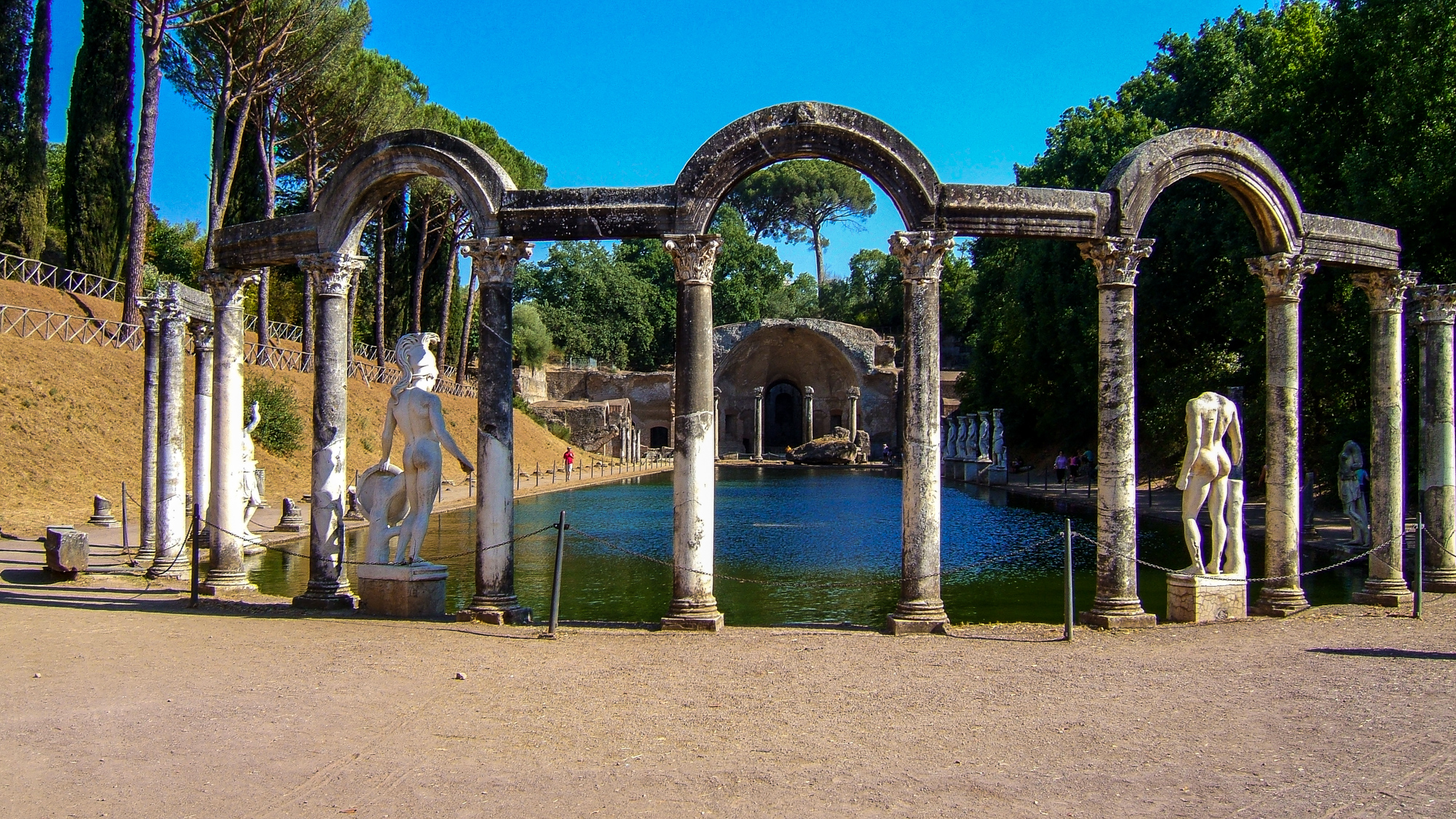 a statue standing in a pond next to a stone fountain