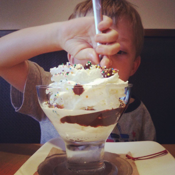 a boy that is holding up a spoon with some ice cream