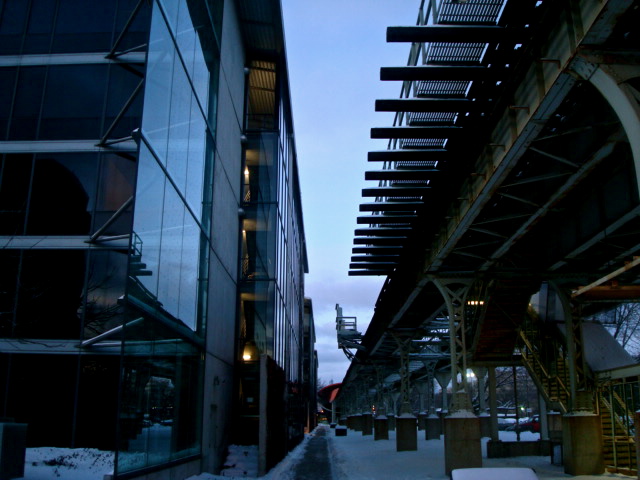 buildings on a snowy street next to a metal bridge