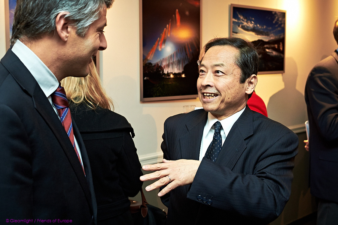 two men in suits are smiling as one talks to the other