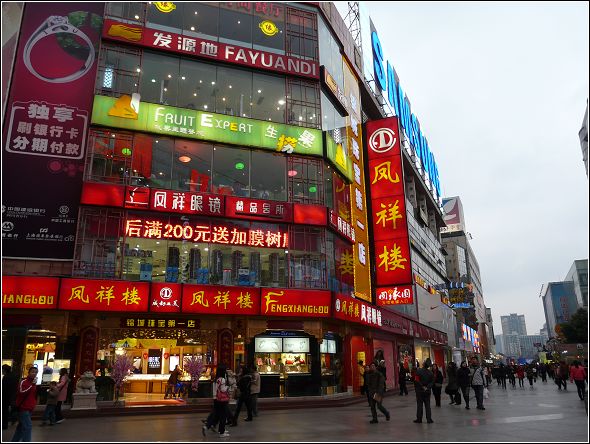 a busy street with pedestrians and a chinese store