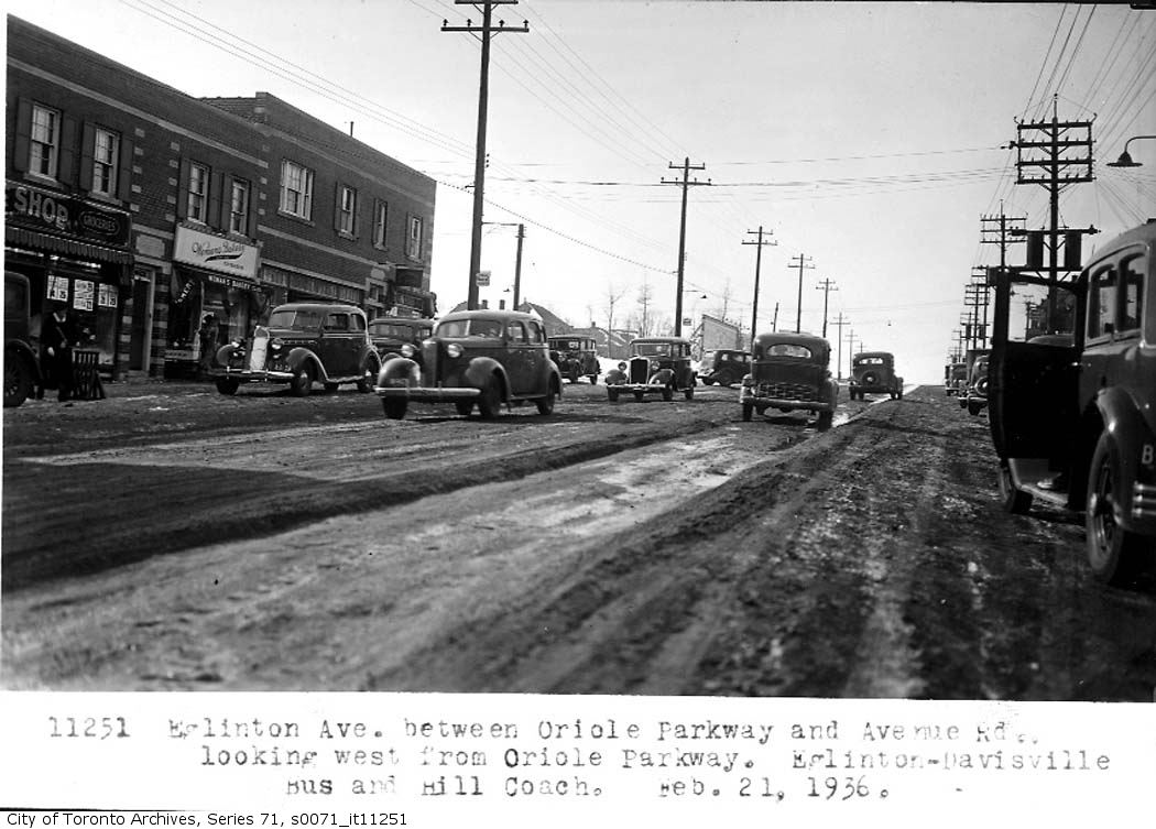 black and white image of cars parked on the side of a city road