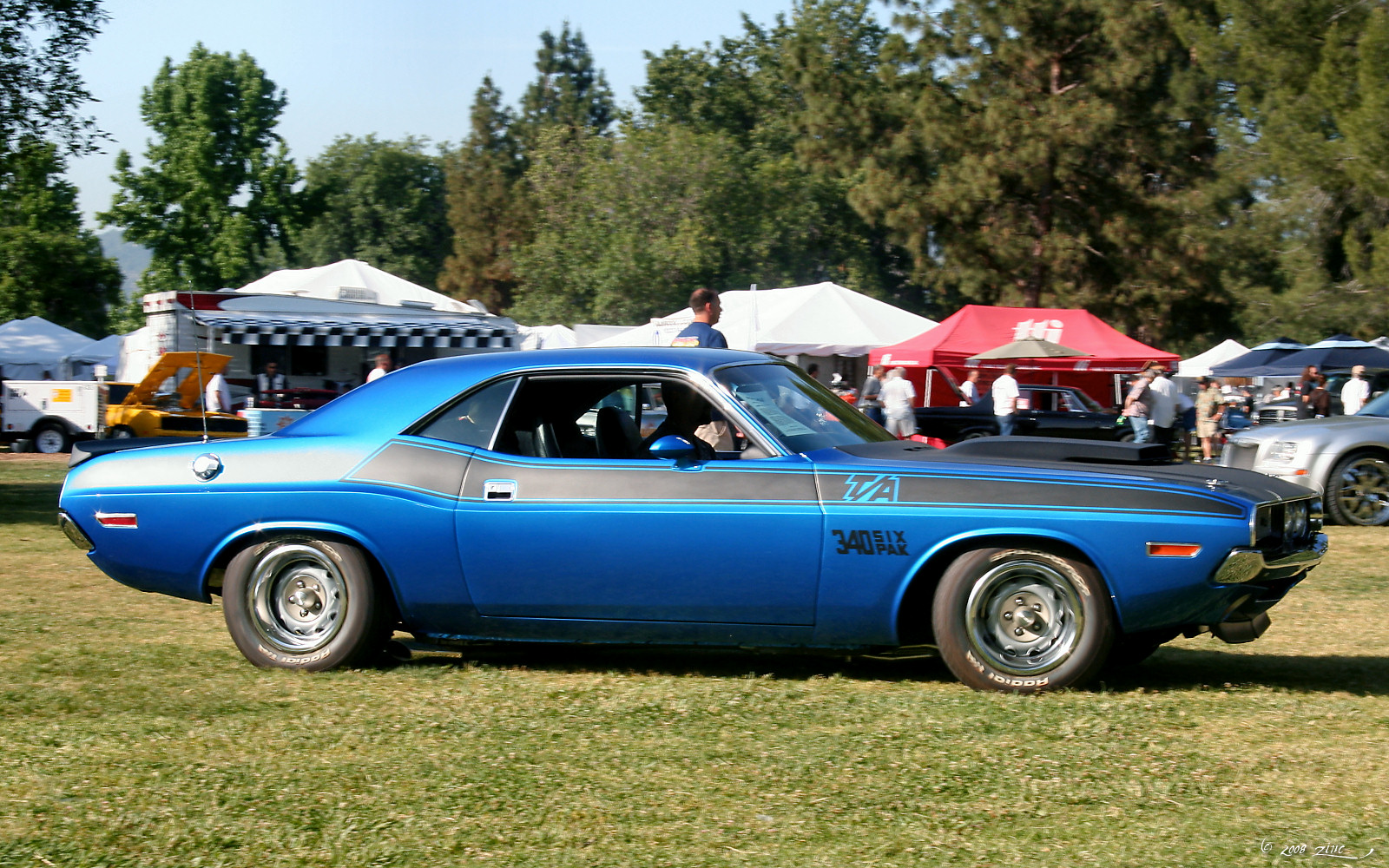 a blue muscle car parked in a field