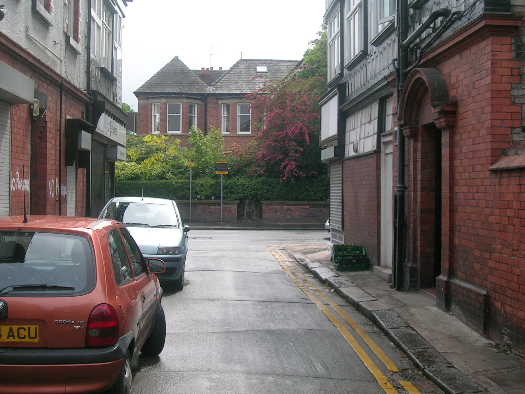 two cars parked in a city street by brick buildings