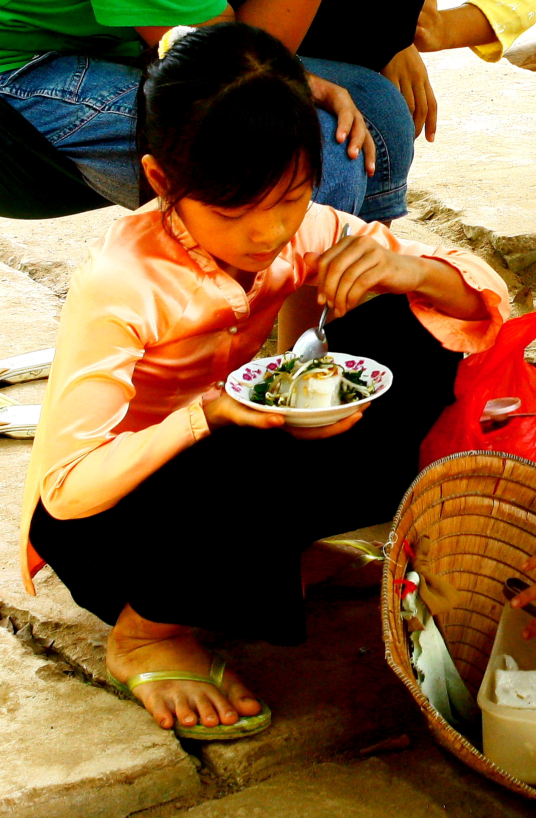 a woman sitting down eating from a white plate