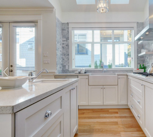 a kitchen with hardwood floors and white cabinetry