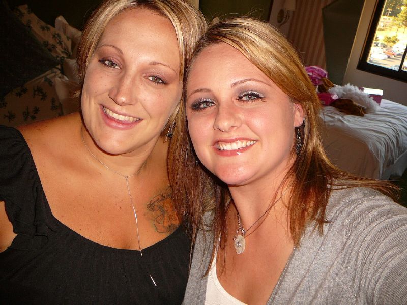 two woman posing for a po together with a table in the background