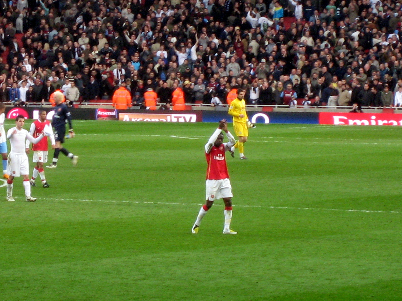 a man in a red and white uniform doing tricks on a soccer field with people in the background