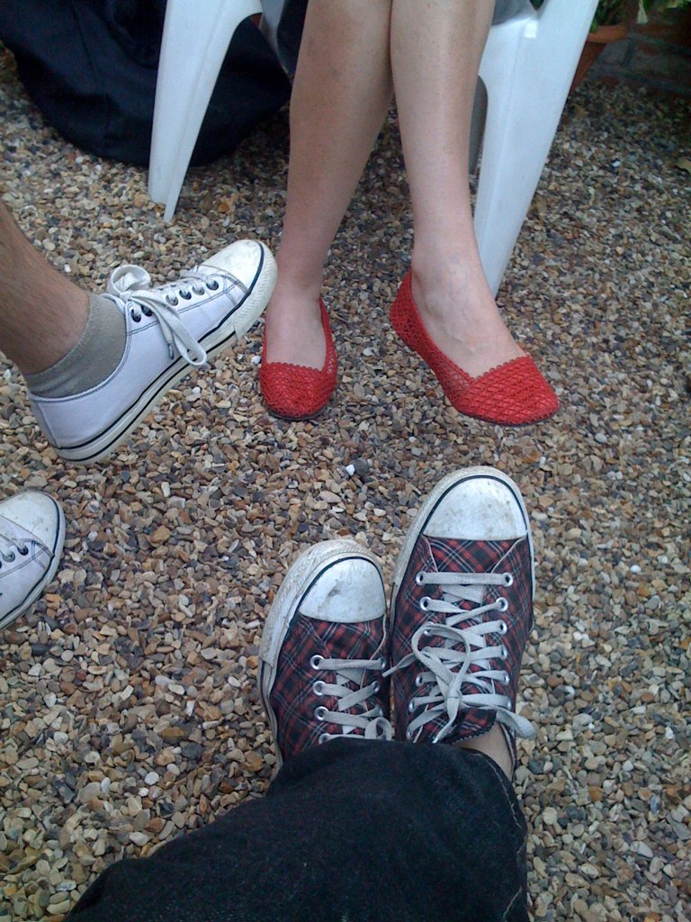 two people standing in a circle wearing red converse shoes