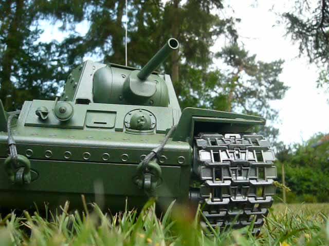 a toy tank sitting in the grass near trees